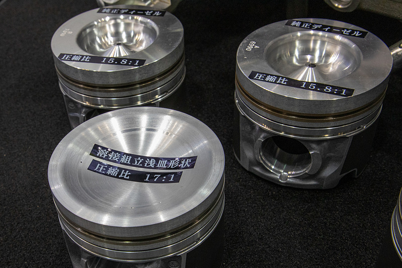 開発中のピストンは圧縮比が17と超高圧縮設定。この圧縮で高回転を維持するとノッキングは出るが、トラックは一定回転数をキープして乗るので、その常用域で最適な圧縮比を求めた結果、こうなったとのこと。発想の転換により生み出されたモノと言える