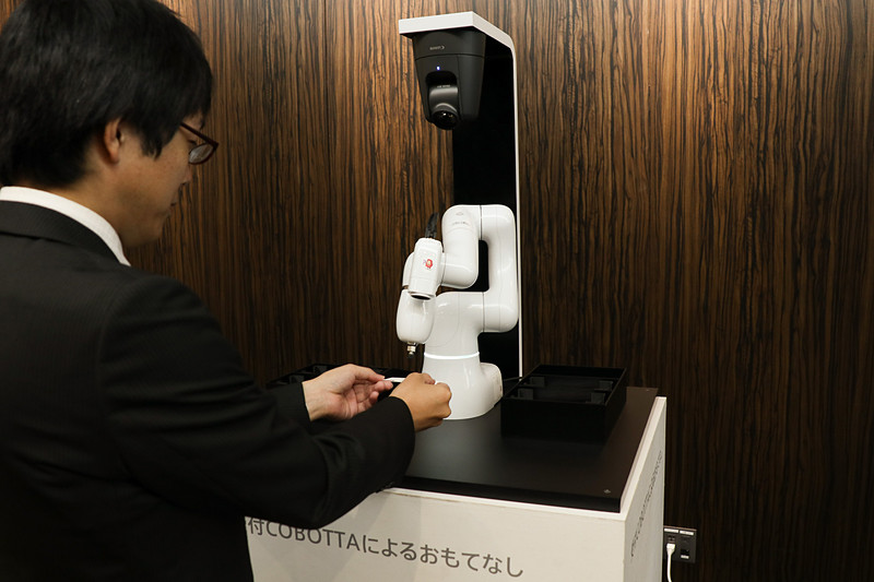 事業方針説明会「デンソー ダイアログデー」の受け付けでは、デンソーウェーブの産業用人協働ロボット「COBOTTA」も受け付けを担当。アーム先に取り付けた吸引ユニットで来場者から名刺を受け取り、お返しとしてカードタイプの記念品を渡していた
