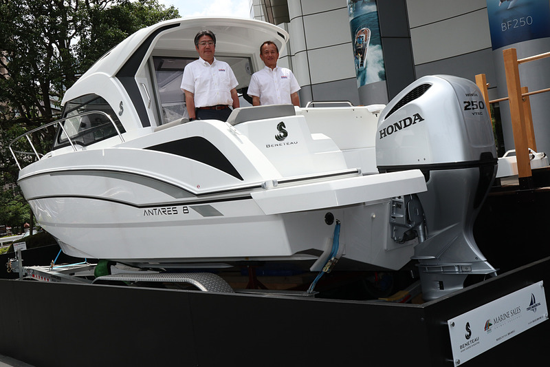 「ホンダウエルカムプラザ青山」の玄関前スペースに展示されたクルーザー。キャビンに立っているのは本田技研工業株式会社 執行役員 ライフクリエーション事業本部長 奥田克久氏（左）と本田技研工業株式会社 執行役員 ライフクリエーション事業本部 マリン事業部長 佐藤公亮氏（右）