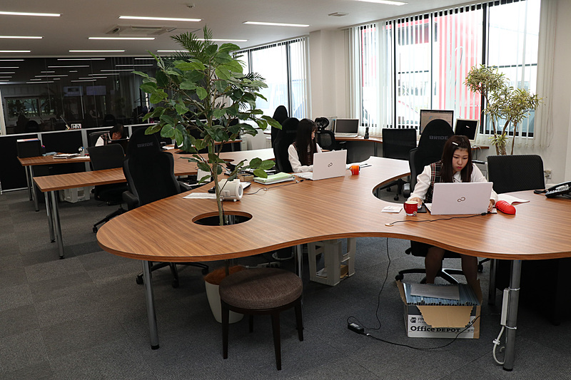 事務所スペースには観葉植物が置かれ、ブリッド製のスポーツシートを流用するオフィスチェアを採用