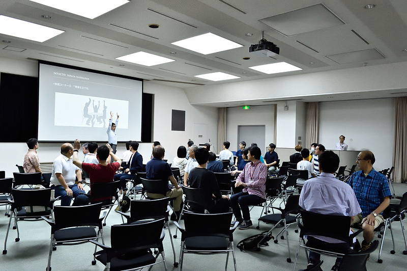 猿渡健一郎氏の講演は、マツダが提唱している「人間中心」の開発哲学についての内容。クルマの開発に人間が持つ機能や感覚などを取り入れていることを説明し、車両のスイッチを押したときの人間の感覚を、来場者にスイッチに触ってもらいながら解説していた