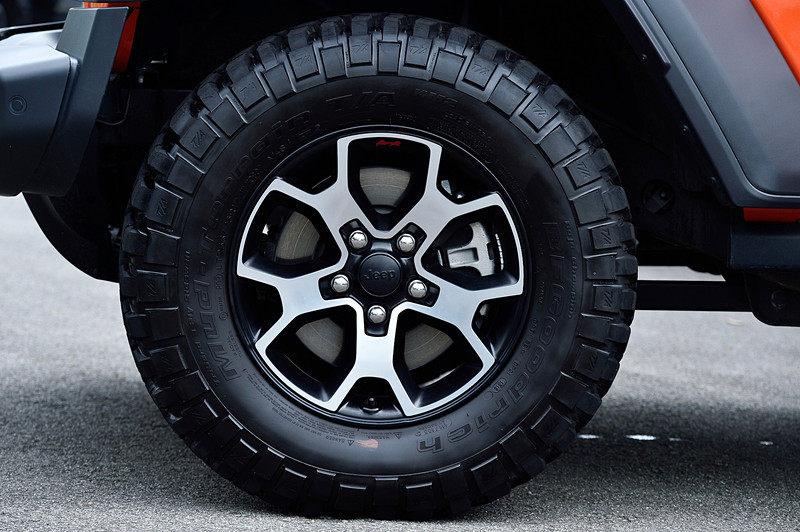 試乗車のアンリミテッド・ルビコンではルビコン専用の17インチアルミホイールにBFGoodrichブランドのオフロード用4×4ラジアルタイヤ「Mud-Terrain T/A KM2」（LT255/75R17）を装着。エクステリアでは標準仕様のサイドステップを車体のダメージを緩和するロックレールへと変更したほか、ダークグレーのアクセント入りフロントグリルや、ブラック仕様のハードトップおよびフェンダーフレア、フロントフェンダーのRubiconデカールなどが特徴になっている