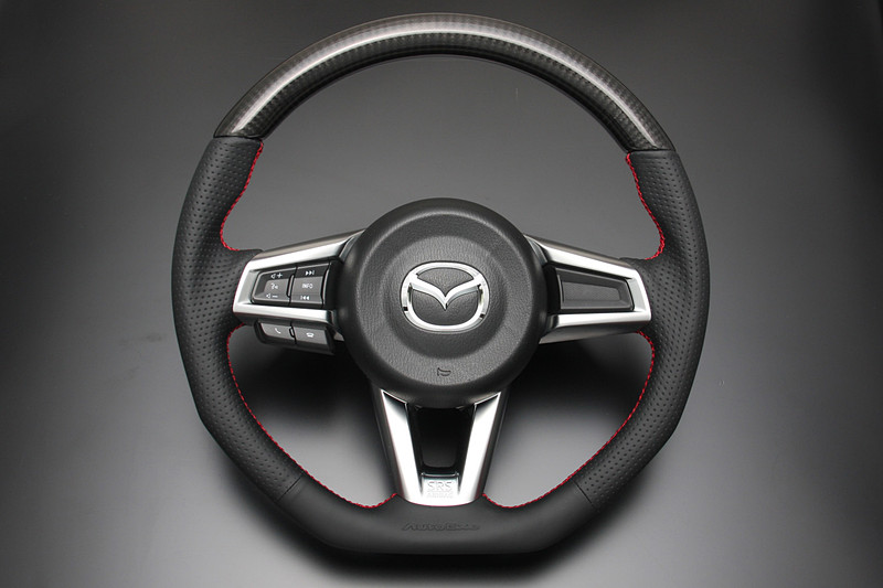 トップ部にリアルカーボンを採用するとともに、柔らかく耐久性のあるナッパレザー、ボトム部に配したAutoExe型押しロゴなどでスポーティさと高級感を両立