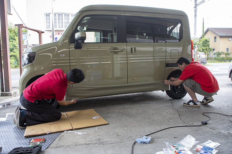 今回の施工風景。この日はクルマ整備の工場が休みの日だったので、グッズ製造工場前で施工した