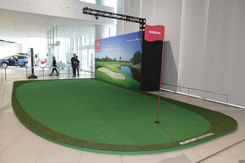 日産グローバル本社ギャラリーに特設された体験グリーン。グリーン上に設置した3つのカメラでグリーン全体の情報をピップアップし、コンピューターで解析。カップまでの移動に必要な動きをゴルフボールにワイヤレスで指示する仕組み