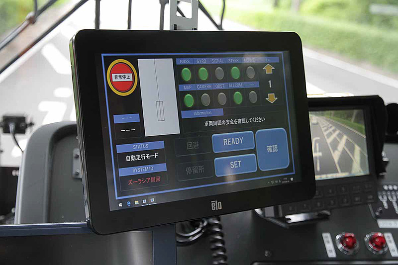自動運転バスの運転席。運転席の左側に備えているのは自動運転用の液晶モニター。自動運転はこのモニター上で操作を行なう