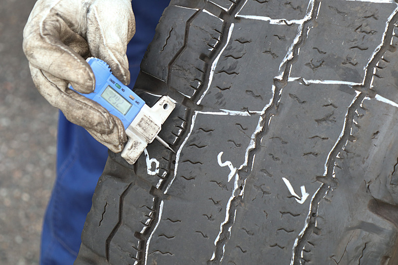 どれだけリグルーブ可能か専用の計測器でチェックする。トレッド面にチョークで書かれた数字がリグルーブ可能な深さ（mm）。トラック・バス用のタイヤは直径が大きいため遠心力の影響が強く、とくに中央部分が偏摩耗しやすい