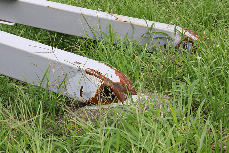 国道沿いに設置されていた金属製の広告看板。支柱の根元からぐにゃりと折れ曲がっている