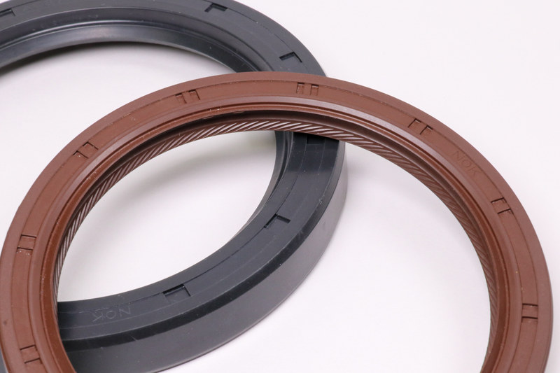 オイルシールはオイルの漏れを防ぐため、回転している時に大気側からわずかに空気を吸い込んでいることをご存じだろうか。それを増幅しているのが写真手前のオイルシールの内側にある葉っぱの形にも見える凹凸で、これは回転したときに負圧を発生させる形状になっていて、これにより外に漏れようとするオイルを引き戻す効果があるという。この形を採用しているのはNOK製品のみだ