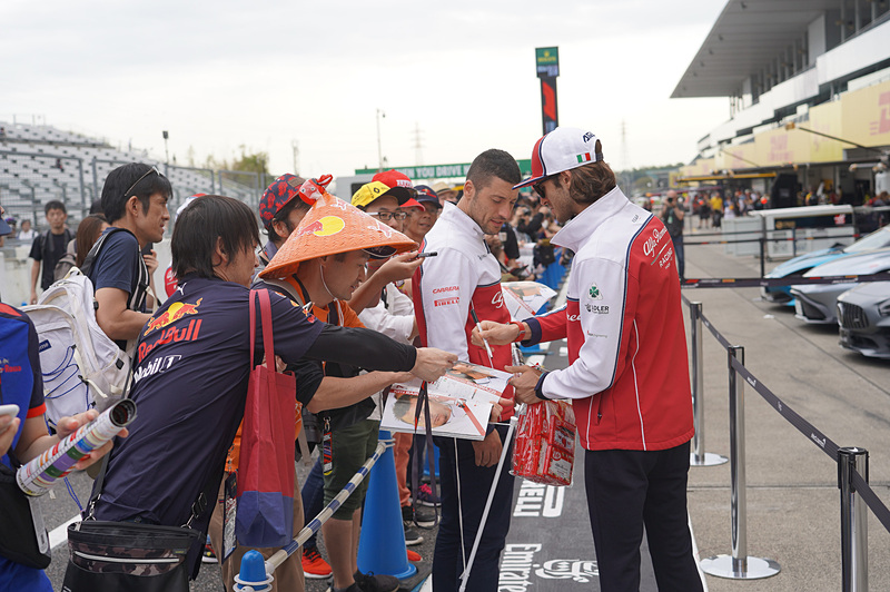 アルファ ロメオのアントニオ・ジョビナッツィ選手がピットウォーク中に登場してファンにサインのサービス