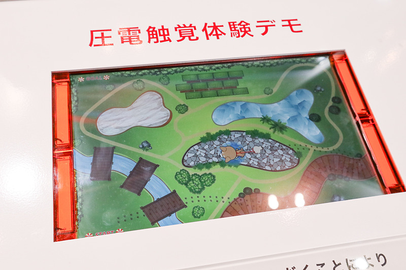 太陽誘電のブースでは圧電アクチュエータでディスプレイを振動させ、触感を変化させるデモを行なった。指でなぞると石畳や池、砂場などをなぞった際に指に伝わる感覚が変化する