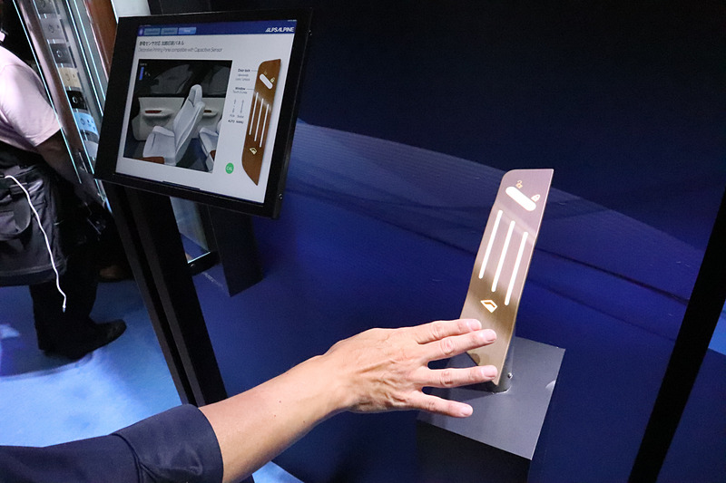 アルプスアルパインでは操作デバイスの参考展示として、静電センサ対応加飾印刷パネルを展示した。タッチするスイッチを加飾したパネルに備えることができ、インテリア性と操作性を両立できる。展示はパワーウィンドウと集中ロックの操作