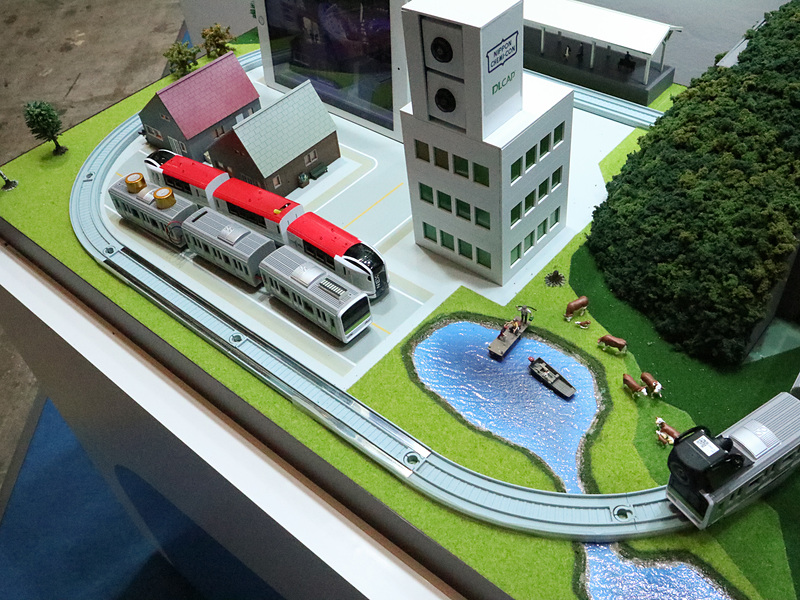 車載カメラとキャパシターのデモを「プチ電車」で再現した。カメラ搭載の電車が走行中