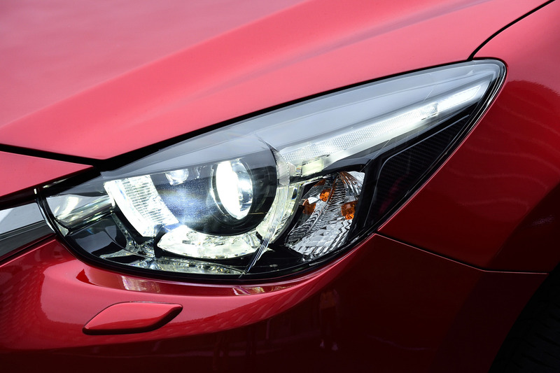 ヘッドライトの比較。左がデミオ、右がMAZDA2となるが見比べるとシグネチャーウイングがライト下部に回り込み、その分ライトがシャープになっている