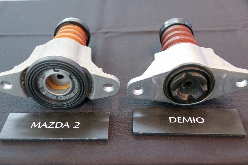 リアダンパーのロッド取り付け部。デミオ（右）ではゴムを介していたのに対してMAZDA2（左）では高減衰ウレタンを介した形に変更