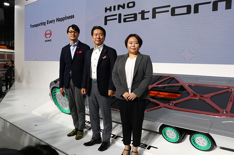 FlatFormerの前に立つ、日野自動車株式会社 代表取締役社長 下義生氏（中央）とデザイナーの関口祐治氏（左）、開発者の小林こずえ氏（右）