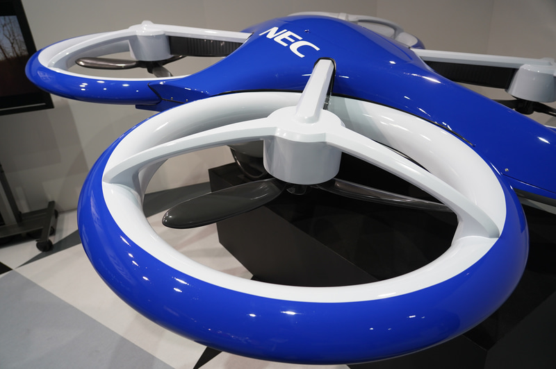 NECが展示した空飛ぶクルマの模型。空港と都市などを結ぶ交通システムになる。見た目はドローンのようだ