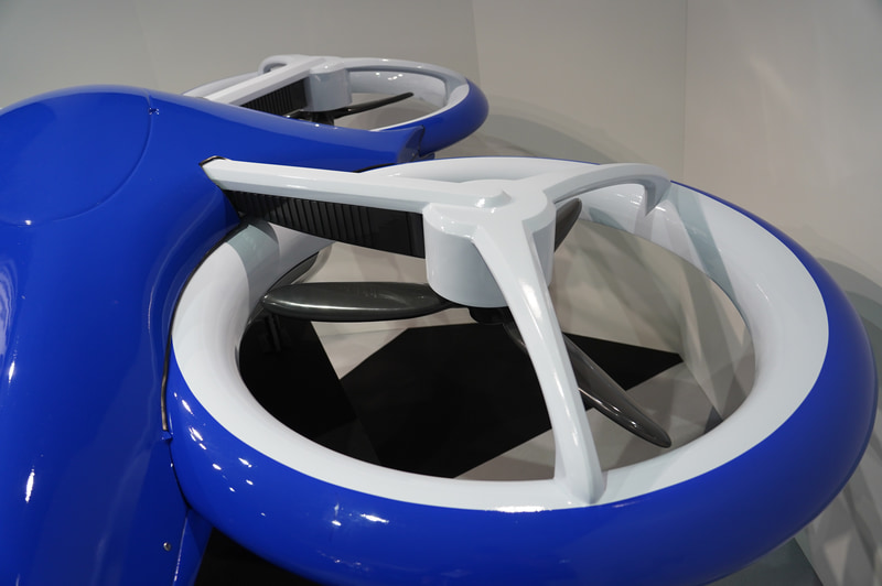 NECが展示した空飛ぶクルマの模型。空港と都市などを結ぶ交通システムになる。見た目はドローンのようだ