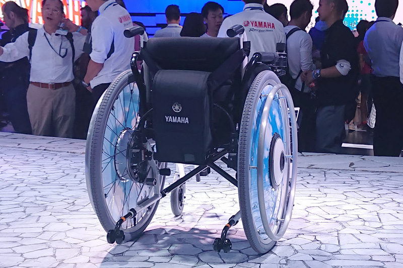 背面に取り付けられたケース内にはバッテリーが収納され、これで左右駆動輪の中心にあるモーターを動かす仕組み。1回の充電で、ニッケル水素バッテリーなら15km、リチウムイオンバッテリーなら30kmの走行が可能