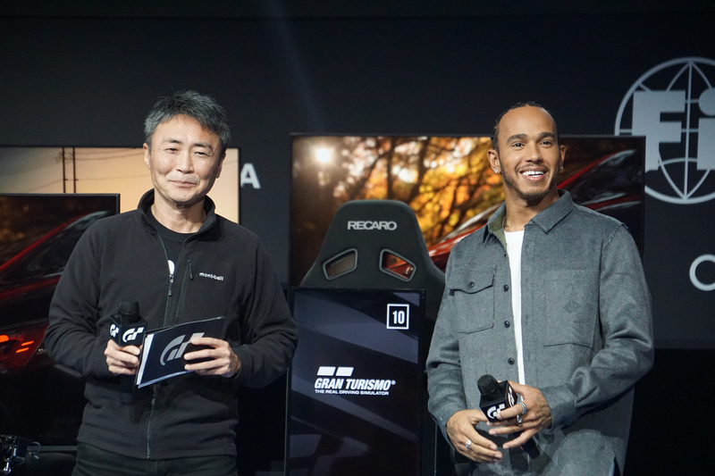 「FIA グランツーリスモチャンピオンシップ ワールドファイナル in モナコ」大会会場に登場した「グランツーリスモ」プロデューサーの山内一典氏（左）とルイス・ハミルトン選手（右）