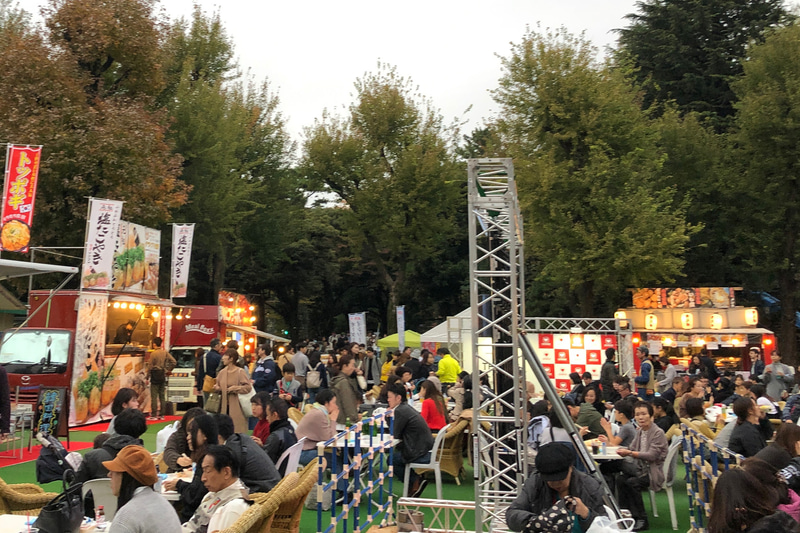 2019神宮外苑いちょう祭りの「にこにこパーク会場」はこんな雰囲気。11の店舗とドリンクコーナーが集まっています。イチョウ並木のすぐ横にある「権田原会場」はもっと広くて、20店舗がズラリ。あちこちから芳醇な香りがただよい、みんないい顔でグルメを楽しんでいました。ドライバーは飲酒ご法度ですが、生ビールも売っています！