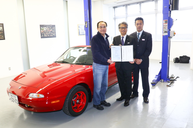 レストアが完了したロードスターの前に立つ、左からオーナーの板垣氏、マツダ株式会社 商品本部 ロードスターアンバサダー 山本修弘氏、テュフ ラインランド ジャパン株式会社シニアセールスエグゼクティブ 栗田隆司氏