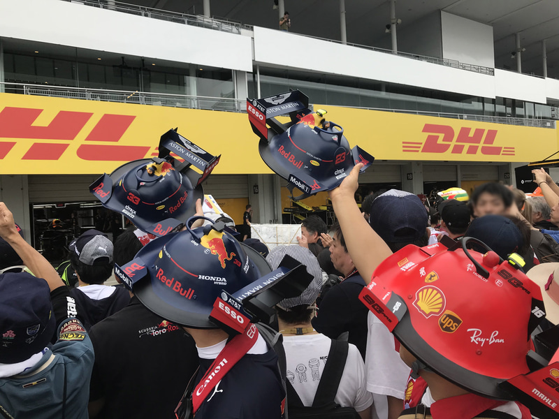レッドブルチームのピットに向かってかぶり物をかざす森本さんと矢吹さん