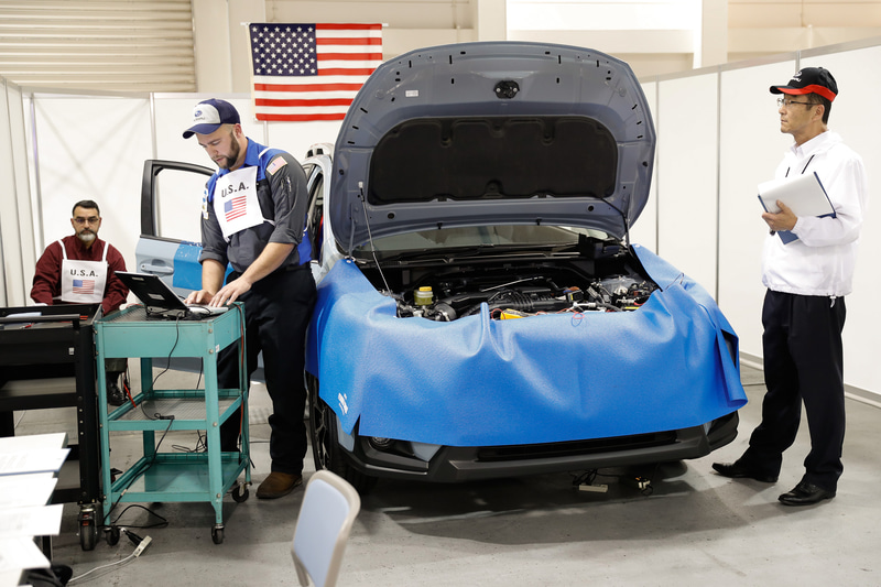 最初は壁際に置かれていた作業台を、作業時間を短縮するため車両の脇に移動。ノートPCのサービスマニュアルを参照して不具合の原因を探す