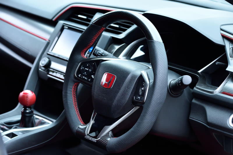 上下はドライカーボン、左右はパンチングレザーを採用し、スポーティかつ高いフィッティングにより安定感のある操作性を実現するスポーツステアリングホイール(8万9100円)。ショートストローク化と、ドライバー側へシフト位置をオフセット。リターンスプリングの変更および、マウントブッシュを排したリジッドマウント化と併せて節度感をさらに高め、確実かつ素早い操作性のシフトフィーリングを実現。クイックシフター(3万6300円)。カーボン製シフトノブ(1万9800円)。アルミ製シフトノブ(1万780円)。写真はアルミ製×本革巻きシフトノブ(1万7600円)。エンジンスタータースイッチ(1万9800円)