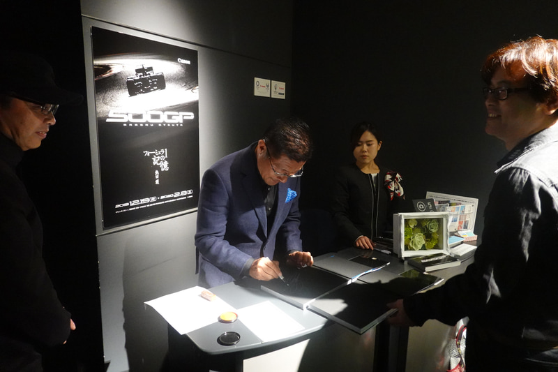 会場で販売する写真集にせっせとサイン。もちろん会場に熱田カメラマンがいたら直接頼んでみるのもよいだろう