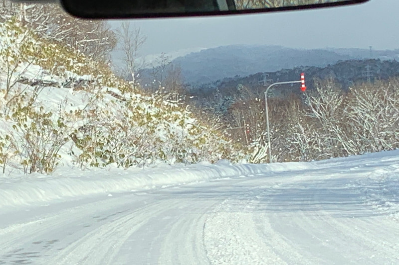 圧雪となった峠道。雪国ならではの路肩表示の矢印がある