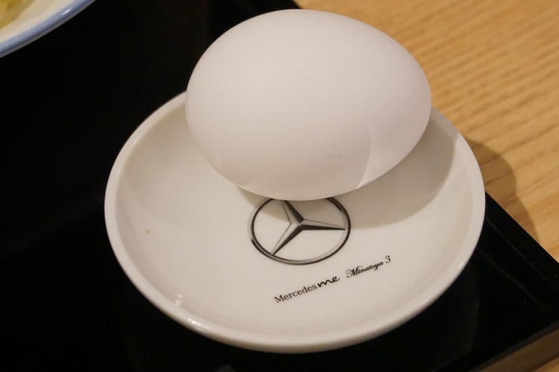 つけ麺タイプの肉そばのMinatoya 3 Vision“Mercedes-AMG GT Atatakai-Nikusoba”。メルセデス・ベンツが港屋とコラボして立ち食いそばをスタート!?。虎ノ門（現在は閉店）、大手町、そして3店舗目がメルセデスミー六本木に登場。メニューは1本勝負、その名もMinatoya 3 Vision“Mercedes-AMG GT Atatakai-Nikusoba”。AMG GT Rに続いてニュルブルクリンクのタイムを更新した新しいマシン名ではなく、創業者・菊地剛志さんがAMGソーラービーム（黄色）をまとったメルセデスAMG GTをイメージして作った肉そば。卵がついて価格は1200円