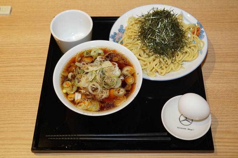 つけ麺タイプの肉そばのMinatoya 3 Vision“Mercedes-AMG GT Atatakai-Nikusoba”。メルセデス・ベンツが港屋とコラボして立ち食いそばをスタート!?。虎ノ門(現在は閉店)、大手町、そして3店舗目がメルセデスミー六本木に登場。メニューは1本勝負、その名もMinatoya 3 Vision“Mercedes-AMG GT Atatakai-Nikusoba”。AMG GT Rに続いてニュルブルクリンクのタイムを更新した新しいマシン名ではなく、創業者・菊地剛志さんがAMGソーラービーム(黄色)をまとったメルセデスAMG GTをイメージして作った肉そば。卵がついて価格は1200円