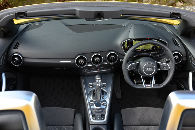TT ロードスター 45 TFSI quattroのインテリア。ステアリングやセレクターノブがロゴ入りの専用品になるほか、ステンレス製ペダルカバーに加え、ウィンドウスイッチ、ミラースイッチのエッジがアルミニウムルックになるオプションのS lineパッケージを装着