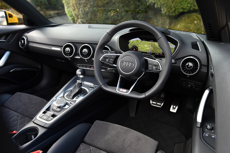 TT ロードスター 45 TFSI quattroのインテリア。ステアリングやセレクターノブがロゴ入りの専用品になるほか、ステンレス製ペダルカバーに加え、ウィンドウスイッチ、ミラースイッチのエッジがアルミニウムルックになるオプションのS lineパッケージを装着