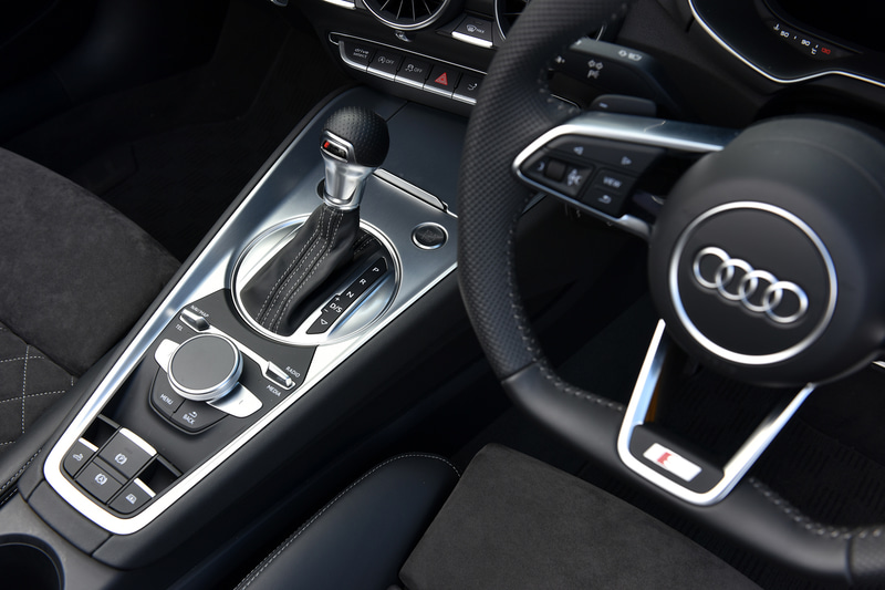 TT ロードスター 45 TFSI quattroのインテリア。ステアリングやセレクターノブがロゴ入りの専用品になるほか、ステンレス製ペダルカバーに加え、ウィンドウスイッチ、ミラースイッチのエッジがアルミニウムルックになるオプションのS lineパッケージを装着