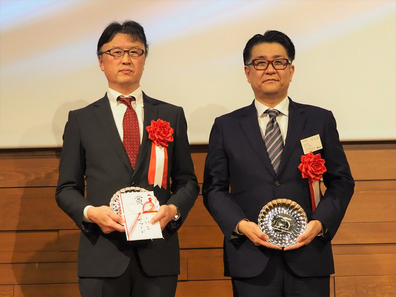 山下健太選手は海外に拠点を移しているためお父さま（左）が、中島選手は海外トレーニング中のため、トヨタ自動車株式会社 GAZOO Racing Company GR企画領域 GRブランドマネジメント部 杉浦宏哉部長（右）が、それぞれ代理で記念盾を受け取った