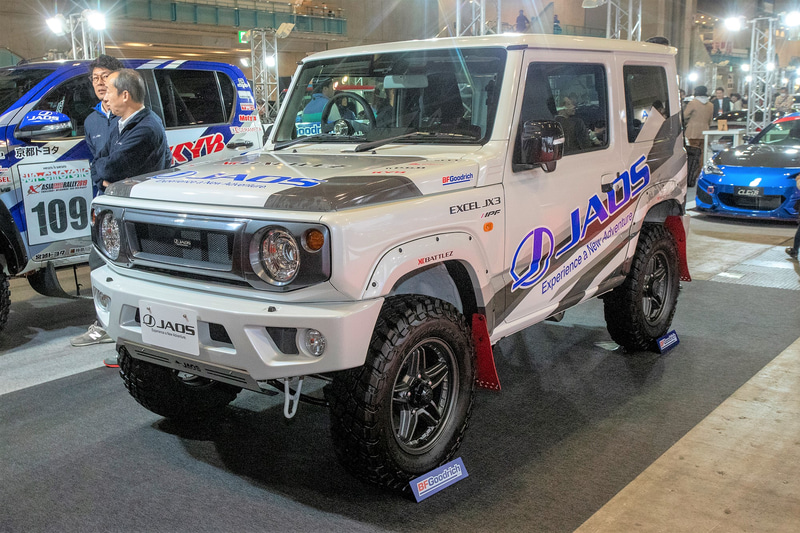 ジャオスが展示する新型ジムニーにはJAOSスポーツカウル（フロント・リア）とJAOSフロントグリル、フェンダーガーニッシュ、ガード類などが装着されている。リアのスポーツカウルは新作でテールランプは丸型4連。レンズにもJAOSのロゴが入っている