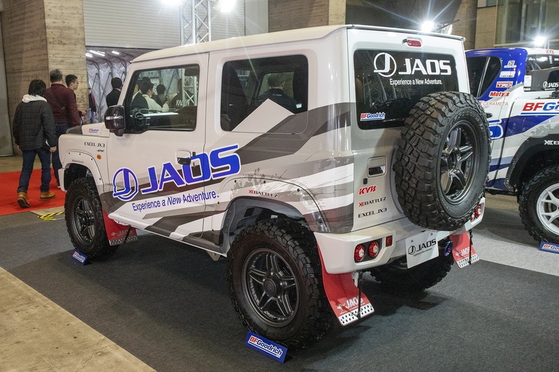 ジャオスが展示する新型ジムニーにはJAOSスポーツカウル（フロント・リア）とJAOSフロントグリル、フェンダーガーニッシュ、ガード類などが装着されている。リアのスポーツカウルは新作でテールランプは丸型4連。レンズにもJAOSのロゴが入っている