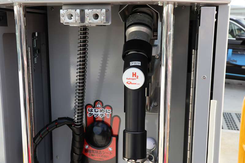 水素の充填は現場に配置されたスタッフが行なうフルサービススタイルだが、将来的には経済性を高めるため、セルフサービス化も視野に入れている。ディスペンサーの上部に設置されているアームとフック付きのワイヤーは、セルフサービス化したときにノズルを手から落として破損しないよう備える設備