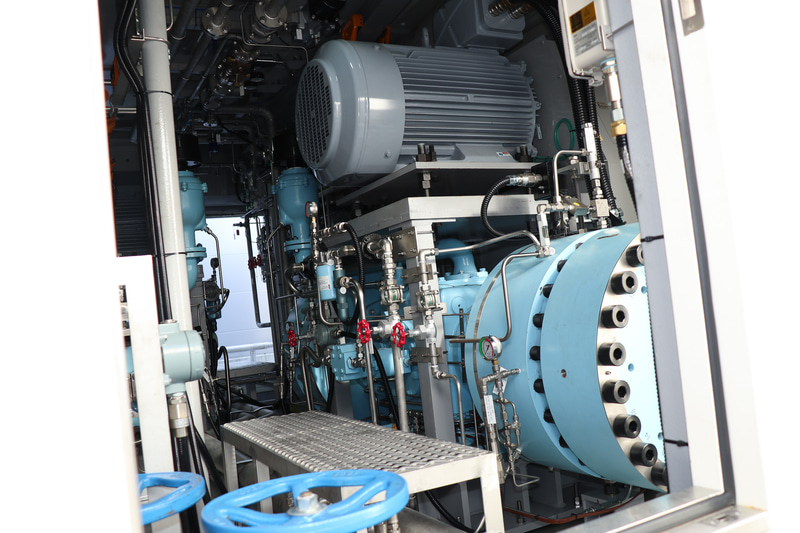 水素を圧縮する「圧縮機」は、日本国内の水素ステーションでの本格的な使用は初となるダイヤフラム式。低い位置にあるブルーに塗装された機械が圧縮機の本体