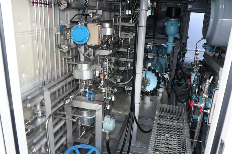 水素を圧縮する「圧縮機」は、日本国内の水素ステーションでの本格的な使用は初となるダイヤフラム式。低い位置にあるブルーに塗装された機械が圧縮機の本体