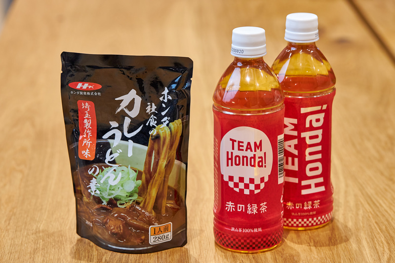 ホンダウエルカムプラザ青山にあるショップで、ホンダ各事業所の社員食堂において金曜日限定で提供される“カレーうどん”を再現した「ホンダ社食のカレーうどんの素」（左）、ホンダ社内のみに販売されていたホンダオリジナル狭山茶「TEAM Honda！赤の緑茶」（右）を販売開始