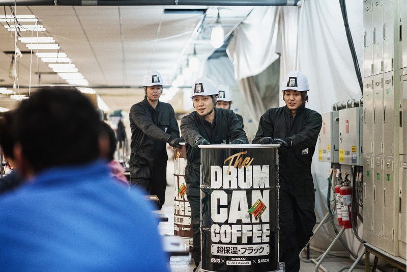 「助太刀アプリ」によって動員された「差し入れ人員」が建設現場へ差し入れを行なう。ファントムブラック（黒）の車両には「ドラム缶コーヒー ブラック」、インペリアルアンバー（茶）の車両には「ドラム缶コーヒー 微糖」を積載する