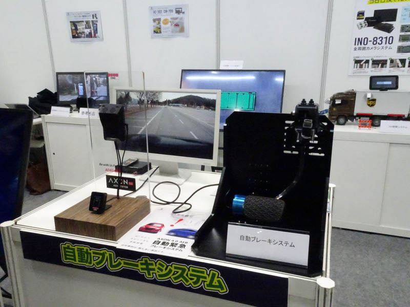 ペダルのアームをモーターで引っ張り上げる簡易型。韓国では50台のバスとタクシーに装着して実証実験を行なっているという。ミリ波レーダーと光学式カメラを用いてTTC（衝突予測時間）の2秒前に警告、1.6秒前に弱いブレーキ（アームを少し引っ張る）、1秒前に強いブレーキ（アームを力いっぱい引っ張る）ことで機能させる