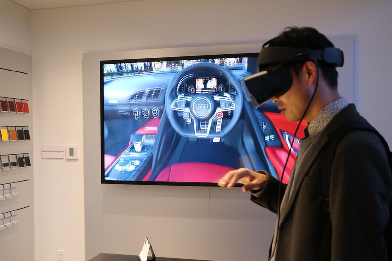 デジタルショールームでは、VRヘッドディスプレイを装着することで、運転席の感覚や車内空間の広さ、カラーリング、クルマの外観、屋根の開閉、ドアの閉まる音までリアルに再現されて疑似体験することができる