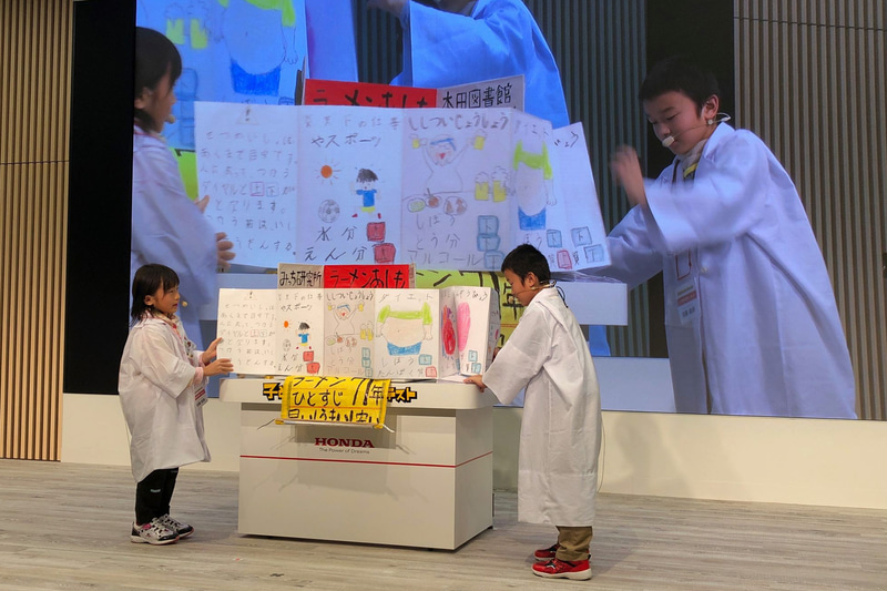 低学年の部の最優秀賞に輝いたのが、静岡県から応募してくれた佐藤兄妹の作品「りょうりのせいぶん　へんかんマシーン」。スラスラと説明するお兄ちゃんに、絶妙な合いの手を入れる妹のかわいさと、病気の人やアレルギーの人でも好きなものが食べられるように、成分が変換できるというアイデアの面白さに脱帽でした。まだ低学年なので、今後の成長に期待しています