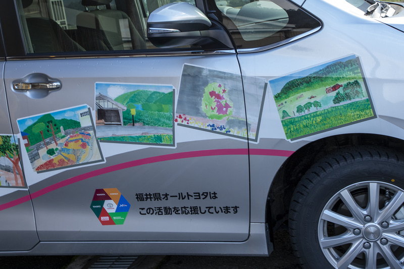 ボディ両サイドに描かれるイラストは、近助タクシーが運行する地区にある志比北小学校の子どもたちが描いたもの
