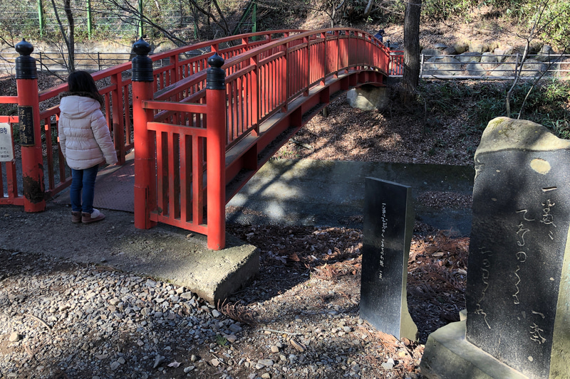 浮島社から万治の石仏へと進むには、この朱色の橋を渡ります。たもとには、小林一茶の句碑が。「一番に 乙鳥（つばめ）のくぐる ちのわ哉」と、夏越しの大祓式に行なわれる「茅の輪くぐり」にちなんだ句のようですね