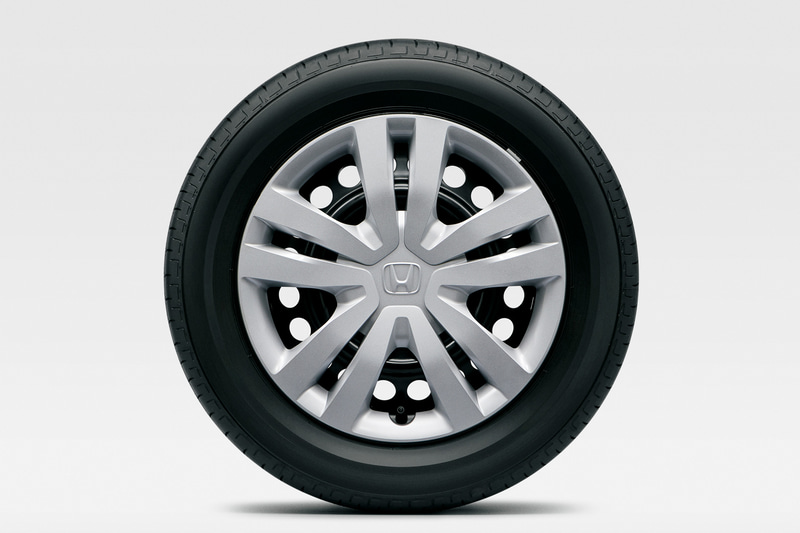 フィット HOME。タイヤはBASICと同じ185/60R15 84Hサイズでホイールはスチールホイール＋フルホイールキャップ。HOMEではNESSで標準装備する16インチのタイヤ＆ホイールのオプション装着も可能